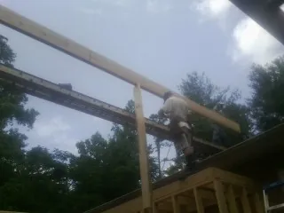 Carpenter setting a ridge beam over a new addition frame — Ice Dam Removal by Roofing Brothers in Noble