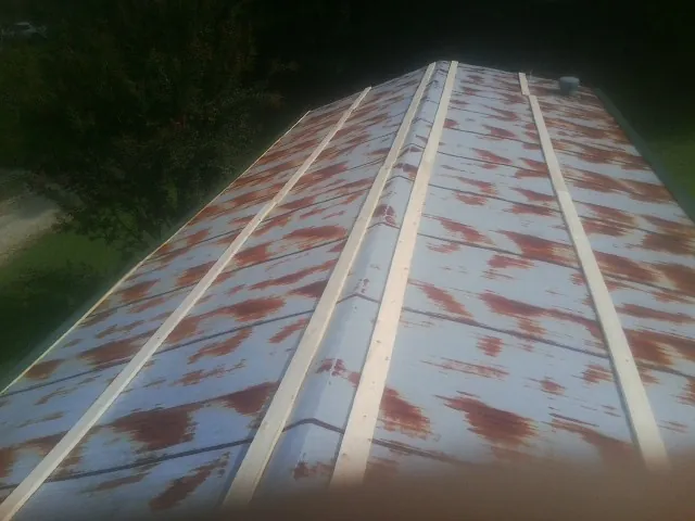 Rusted metal roof panels with new wood purlins before replacement — Storm Damage Roof Repair in Noble by Roofing Brothers