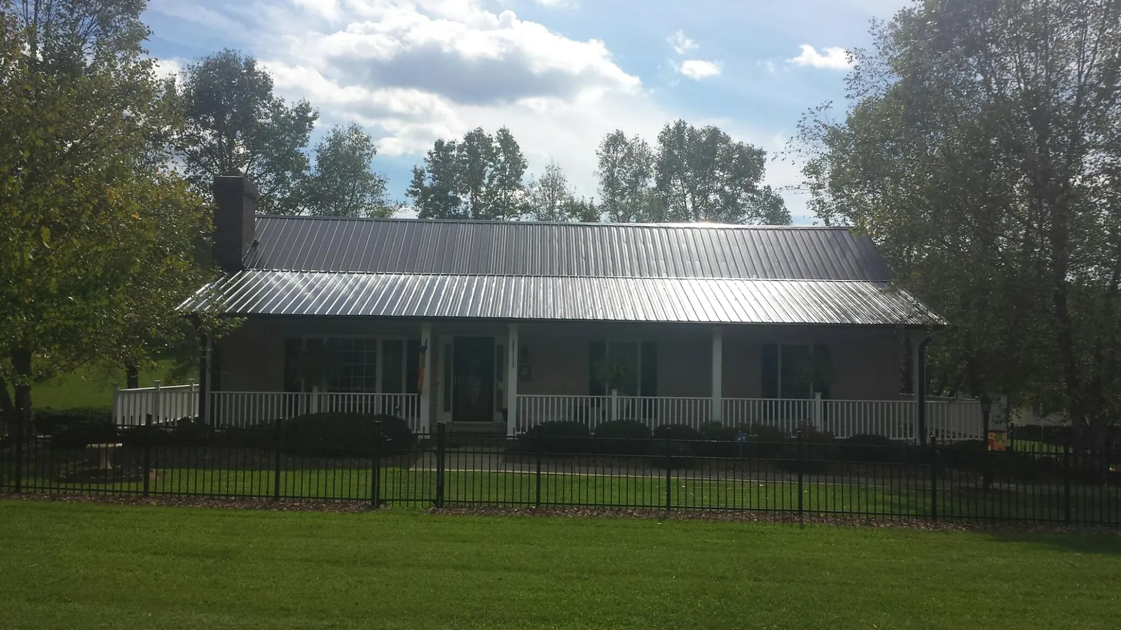 Gray metal roof on a brick ranch with a full width front porch — Gutter Guard Installation work by our crew in Noble