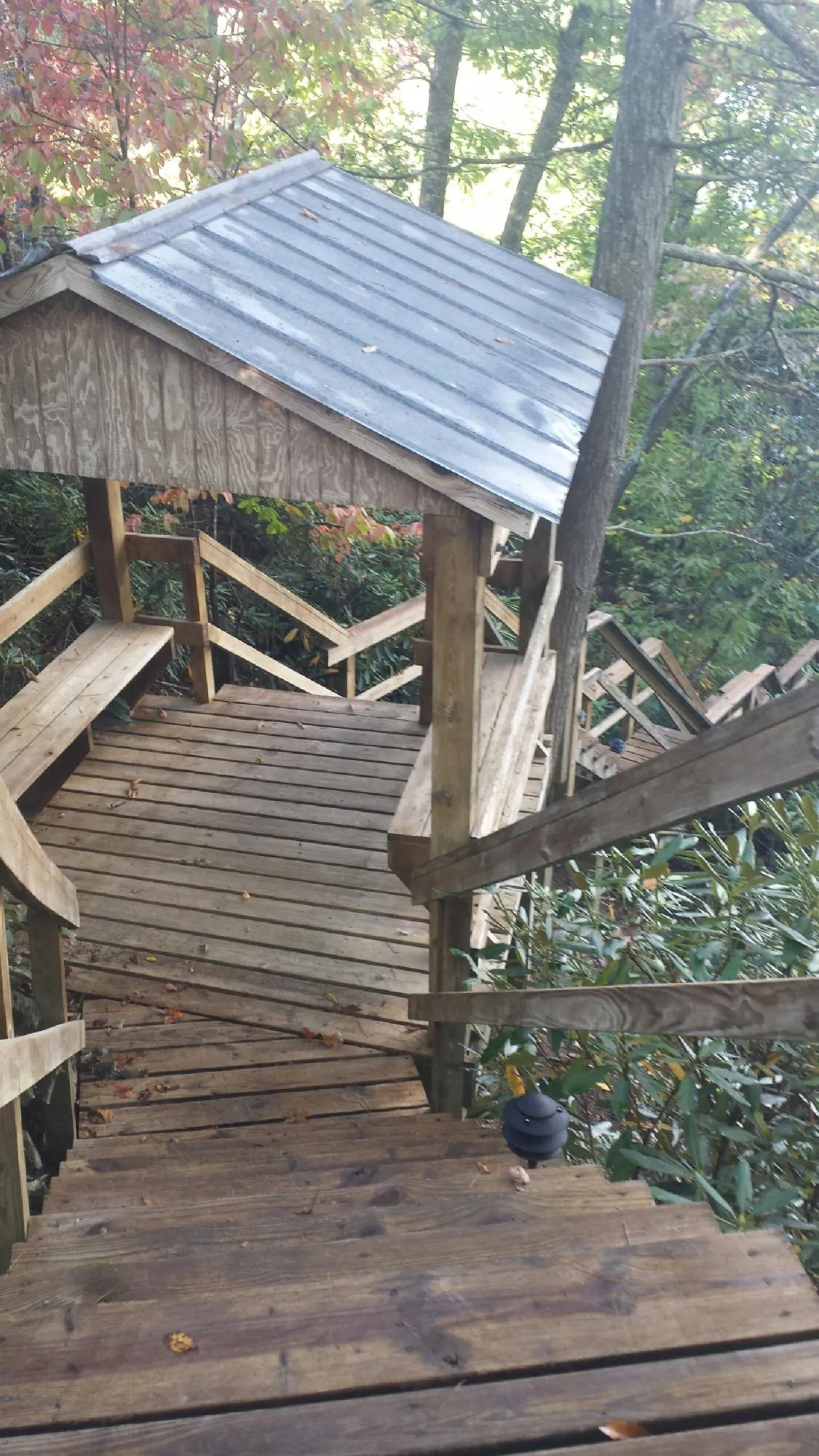 Metal roofed shelter over wooden steps on a wooded walkway — Skylight Repair & Installation work by our crew in Noble