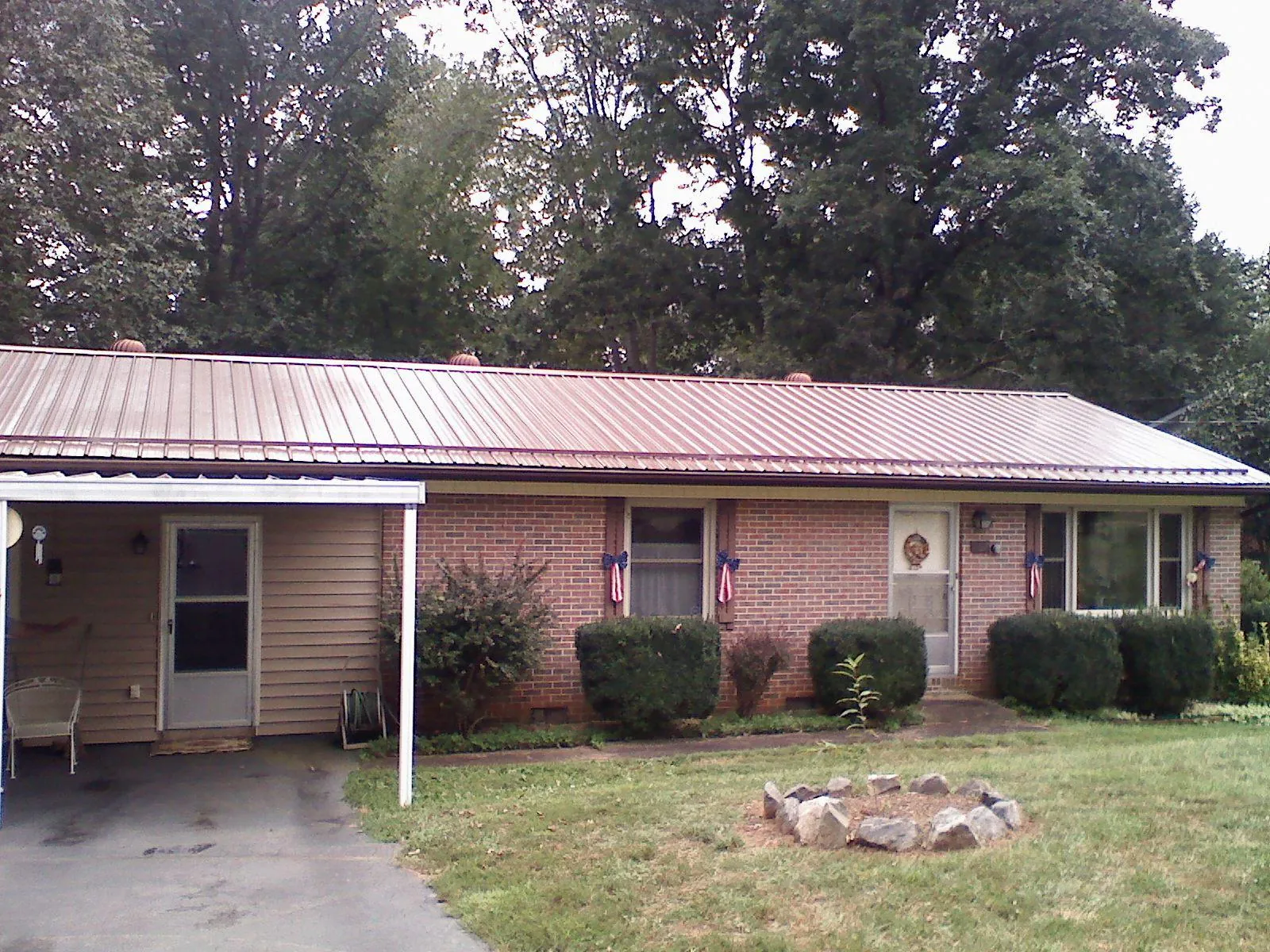 Bronze metal roof and carport on a brick ranch home — Roof Repair work by our crew in Noble